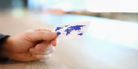 Dłoń trzyma kartę z mapą świata.