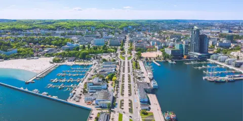 Widok na Gdynię z lotu ptaka. Widać port jachtowy, plażę i zabudowę miejską. Odległość do Wejherowa jest spora, ale widok zapiera dech.