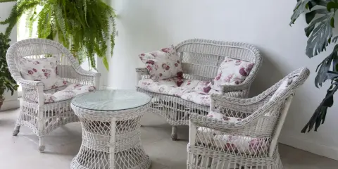 Conjunto de muebles de mimbre blanco con cojines florales, ideal para restaurar muebles de mimbre y darles un toque fresco.