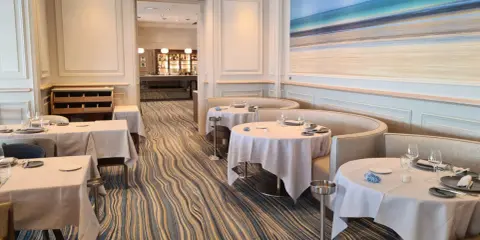 Élégant bistro à Saint-Malo, tables dressées, ambiance chic avec une fresque marine au mur.