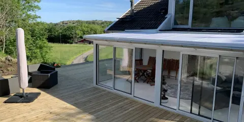 Ny slipad altan med glasveranda och utemöbler. Perfekt för att njuta av sommaren.