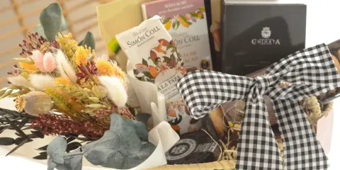 Cesta de regalo con chocolates, flores secas y un lazo de cuadros. Ideal para aprender como hacer una cesta de chuches para regalar.