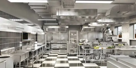 Cocina profesional de acero inoxidable con suelo de baldosas a cuadros, campanas extractoras y equipamiento listo para cualquier tipo de cocina.