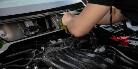 Mechanik sprawdza, dlaczego przekaźnik cyka, a rozrusznik nie kręci. Widok na silnik i przewody.