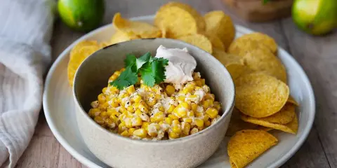 Krämig majsrätt med en klick gräddfil och koriander, serverad med tortillachips. Perfekt som tillbehör eller dipp.