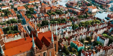 Widok z lotu ptaka na zabytkowe miasto z ceglaną katedrą i kolorowymi kamienicami.