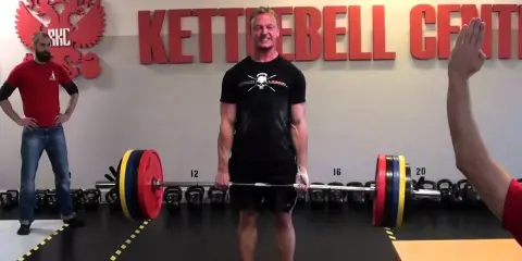Man i gymmet gör sig redo för ett tungt intervall pass med skivstång.