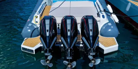 Trois puissants moteurs hors-bord noirs et rouges, prêts à propulser une chaise de luxe sur l'eau.