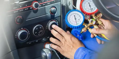 Mechanik sprawdza, ile czynnika do klimatyzacji pozostało w samochodzie, używając manometrów.