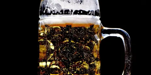 Złocisty lager w szklanej, tłoczonej kuflu, z obfitą pianką. Idealny rodzaj piwa na gorący dzień.