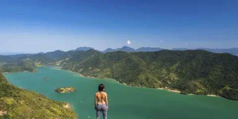 Frauenblick auf die grüne Bucht von Paraty, Brasilien, mit bewaldeten Bergen und Inseln.