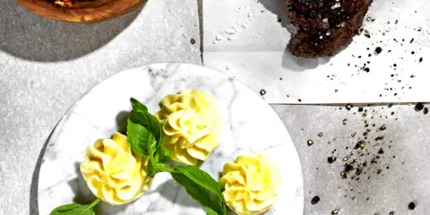 Ein Steak mit Kräuterbutter, dazu Kartoffelröschen und eine Schüssel mit einer roten Paste. Perfekt für ein knoblauchbutter rezept.