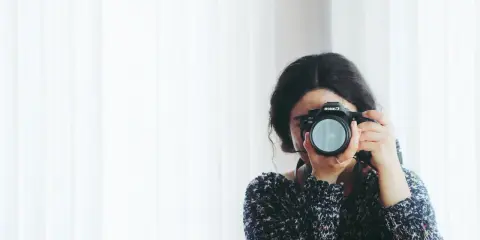 Kobieta z aparatem Canon, skupiona na kadrze. Rozwija swój biznes fotograficzny, łapiąc chwile.