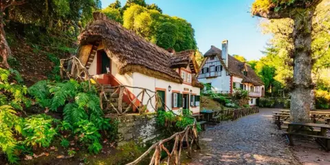 Casitas de cuento con tejados de paja, perfectas para crear viajes inolvidables para adolescentes. Un camino empedrado y vegetación exuberante.
