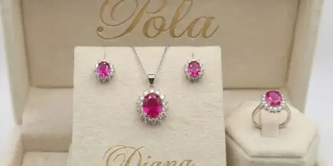 Elegancki komplet biżuterii z różowym korundem i białymi kamieniami, w tym kolczyki, naszyjnik i pierścionek, w beżowym pudełku z napisem "Diana".
