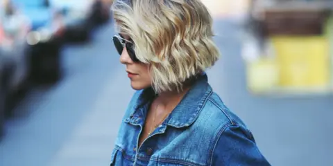Krótkie, blond włosy z falami, uzyskane dzięki prostownicy. Stylizacja na luzie, idealna na co dzień.