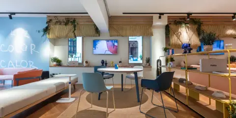 Ambiance lumineuse et colorée pour une idée décoration bureau professionnel. Canapés, table ronde, étagères et plantes créent un espace accueillant.