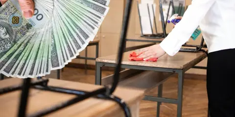 Ręka trzyma banknoty 100 zł. Obok osoba sprząta biurko. Praca Kraśnik od zaraz czeka na Ciebie!