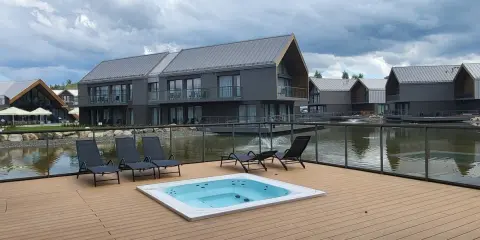 Relaks przy jacuzzi i basenie z widokiem na nowoczesne domki nad wodą. Idealne miejsce na wypoczynek w stylu termy Karkonosze.