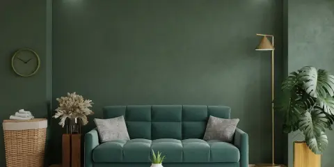 Un acogedor salón con un sofá verde, plantas y una lámpara dorada.