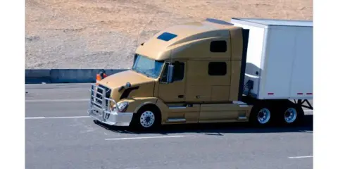 Camión dorado de 40 toneladas en carretera, transportando carga en su remolque blanco.