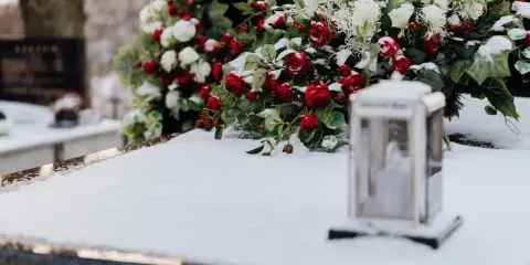 Wieniec dla taty: czerwone róże i białe kwiaty na śniegu, obok lampion.