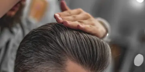 Stylista układa włosy, pokazując, jak mieć gęste włosy chłopak.