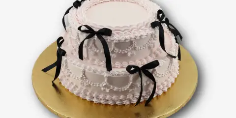 Dwupiętrowy tort w kolorze pudrowego różu, ozdobiony czarnymi wstążkami. Idealny na osiemnastkę, zastanawiasz się, ile kosztuje catering na 18?