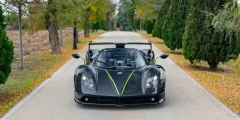 Czarny Pagani Zonda z zielonym akcentem na masce, zaparkowany na alei. Jego cena jest astronomiczna.