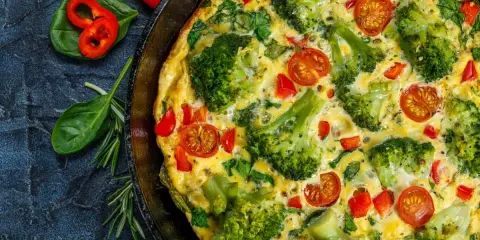 Pyszny omlet na słono z brokułami, pomidorkami i papryką, podany w patelni.