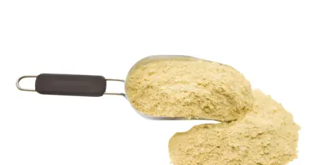 Ein Löffel mit gelblichen Hefeflocken, die als köstlicher hefeflocken ersatz dienen.