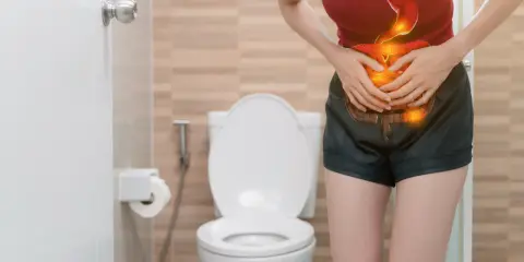 Mujer con dolor abdominal, con ilustración del sistema digestivo en rojo y naranja, frente a un inodoro.