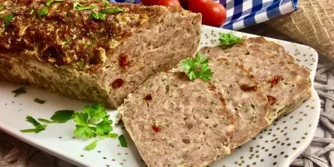 Pyszna pieczeń rzymska na kanapki, pokrojona w plastry, ozdobiona natką pietruszki. Idealna na śniadanie lub kolację.
