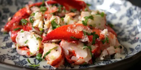 Homard frais servi avec des perles de citron caviar, une recette raffinée pour un plat d'exception.