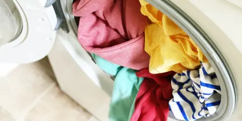 Carga de lavadora con ropa de colores variados, incluyendo rosa, amarillo, turquesa y rayas azules. ¡A ver si se puede lavar ropa blanca con ropa de color sin problemas!