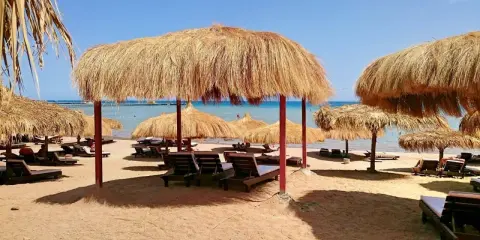 Słoneczna plaża z leżakami i parasolami z trawy. Idealne miejsce na relaks w stylu caves beach resort.