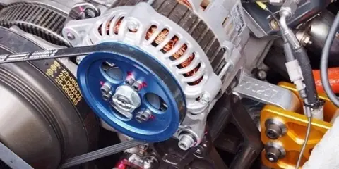 Alternador con polea azul brillante. El cinturón desgastado podría ser la causa del ruido de la polea del alternador.
