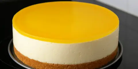 Un délicieux dessert au citron sans cuisson, avec une base biscuitée, une crème onctueuse et un glaçage jaune vif.