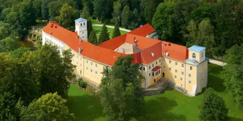 Malowniczy hotel zamek otoczony zielenią.
