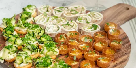 En härlig bricka med veganska snittar: rullade tortillawraps med krämig fyllning och gurka, samt små krispiga tarteletter med ost och marmelad.