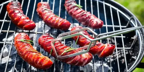 Pyszna kiełbasa z grilla, rumiana i soczysta, z gałązkami rozmarynu, pieczona na węglu.