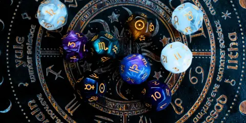 Kolorowe kości do gry na tle zodiaku. Czy to zapowiedź horoskopu tygodniowego dla Wagi?