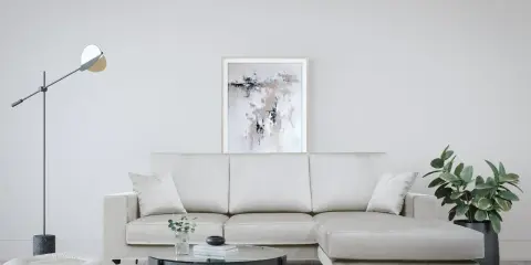 Divano angolare color crema, con tavolino rotondo in vetro e pouf bianco. Le misure del divano angolare sono perfette per questo spazio.
