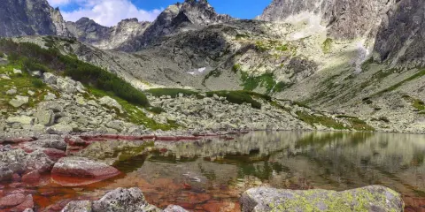 Kamieniste zbocza i skaliste szczyty otaczają spokojną taflę wody w Dolinie Batyżowieckiej.