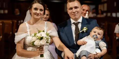 Para młoda z dzieckiem na rękach, podwójna uroczystość: ślub i chrzest w jednym.