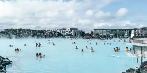 Relaks w Blue Lagoon Islandia. Ludzie kąpią się w mlecznoniebieskiej wodzie geotermalnej otoczonej wulkanicznymi skałami.