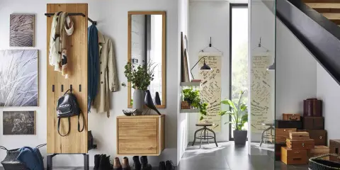 Une entrée dans un salon moderne avec un portant en bois, des manteaux, un sac à dos, des tableaux et une étagère avec des plantes.