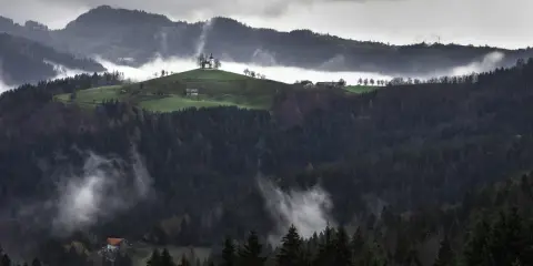 Mglisty poranek w Beskidzie Wyspowym. Kościółek na wzgórzu, domki i las tworzą malownicze atrakcje.