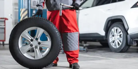 Mecánico con una rueda motriz de coche lista para ser instalada.