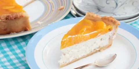 Tranche de cheesecake aux pêches, une gourmandise légère. L'agar agar, son utilisation, assure une texture parfaite.